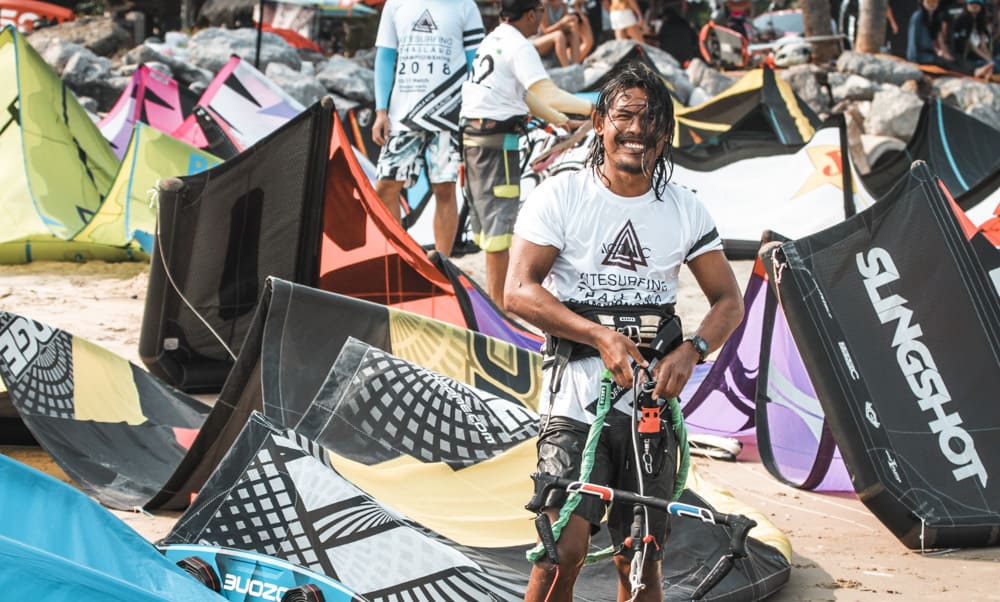 kitesurfer nat en glimlachend op het strand voor zijn kites