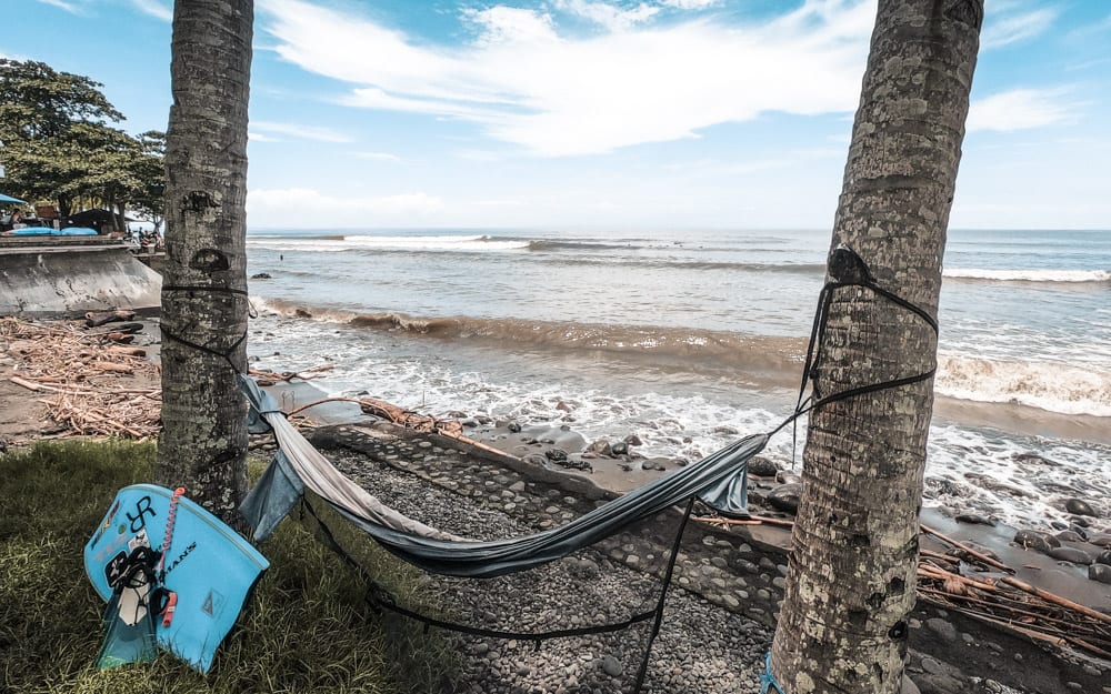 Eine Hängematte, gebunden zwischen zwei Palmen mit Blick auf die Brandung in Medewi, Bali