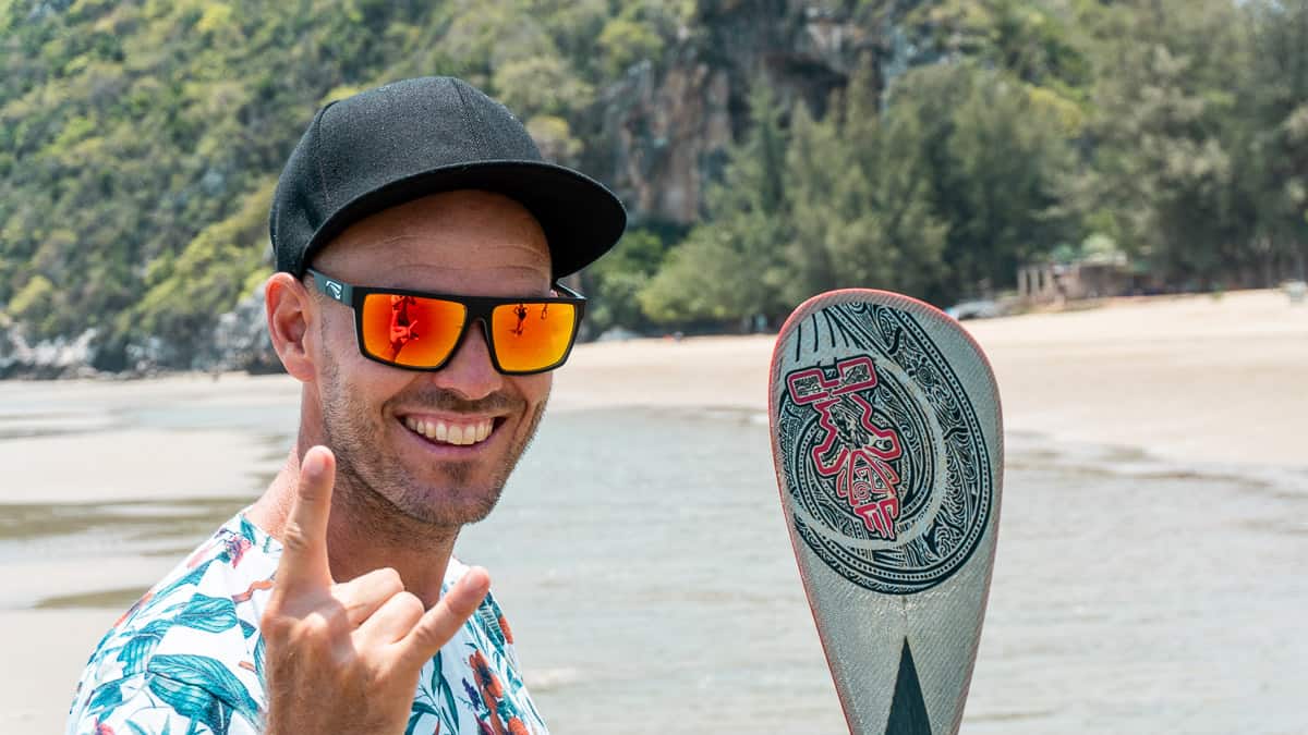 Lachende man met de beste reiszonnebril met Zeiss-brillenglazen op een strand