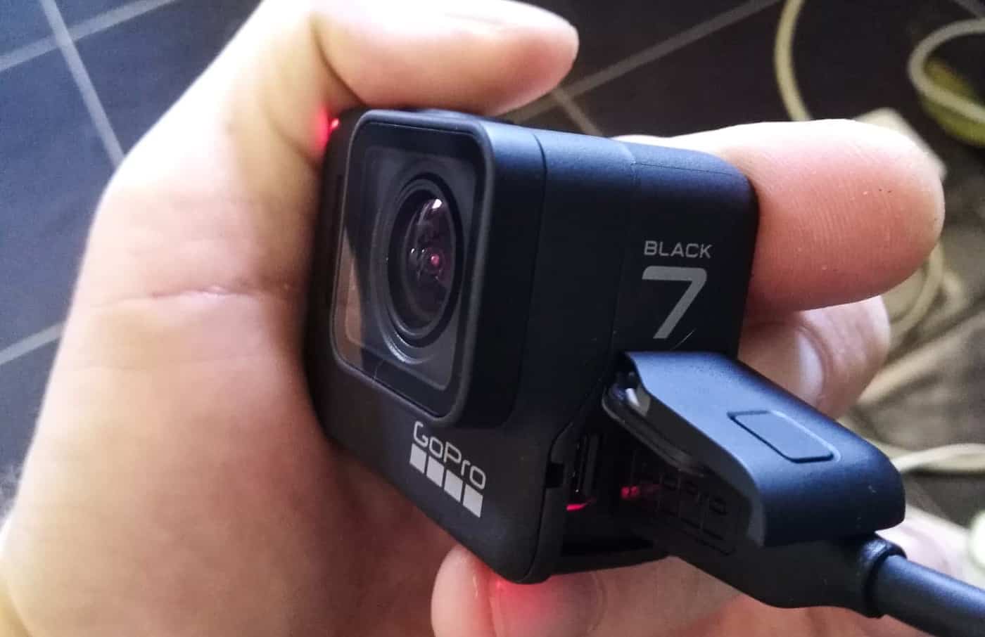 gopro hero 7 black passée en revue dans la main d'un homme avec le logement de la carte SD ouvert