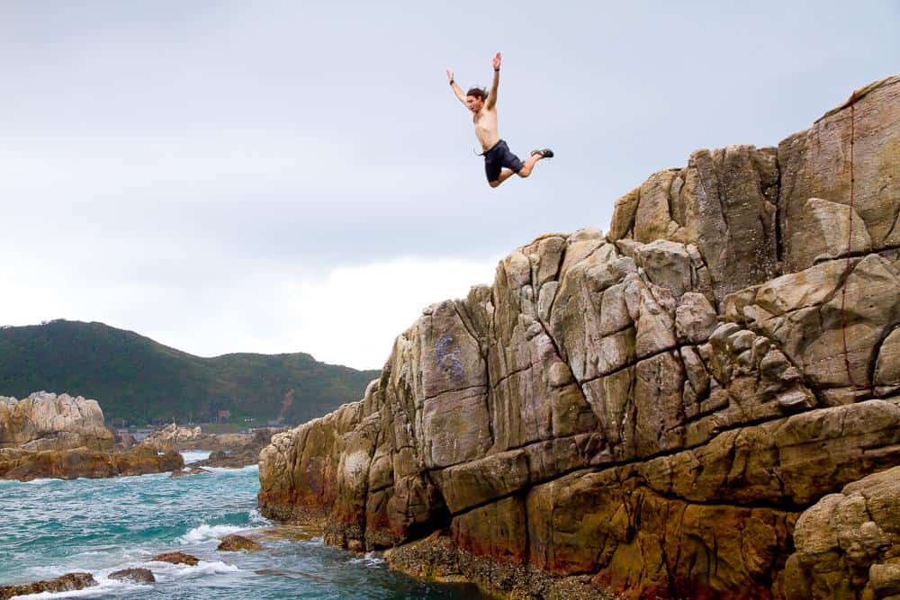 man jumping off cliff into ocean in Taiwan