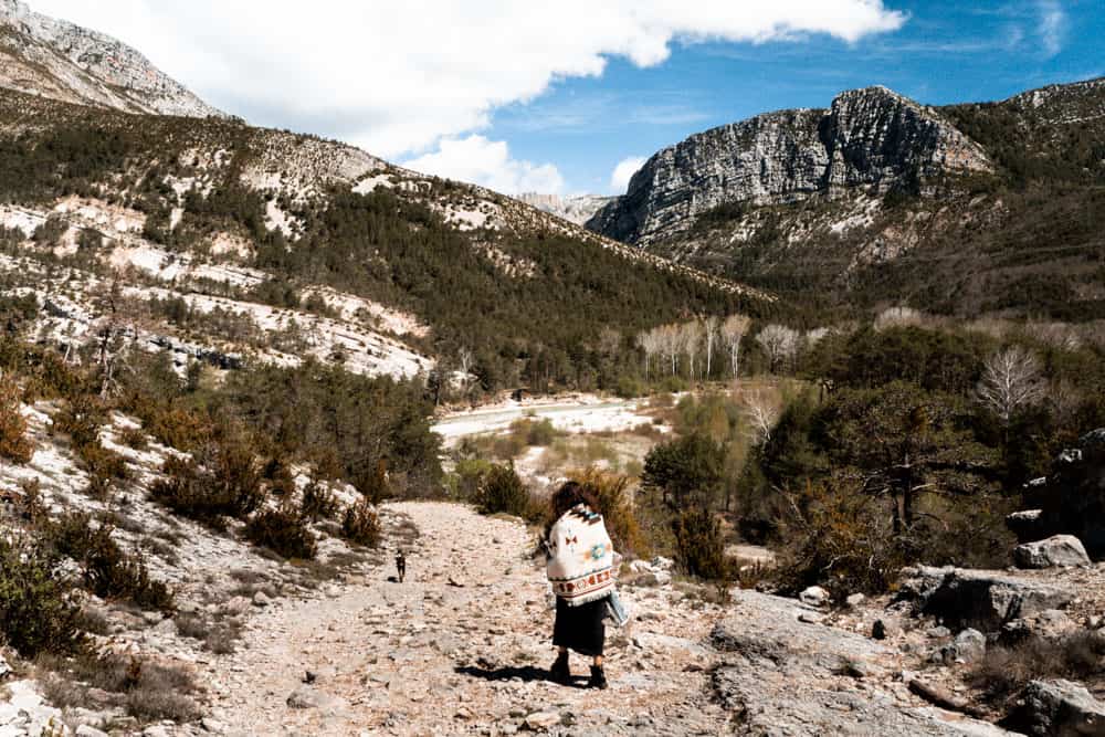 woman and dog walking through rugged mountain landscape along the route napoleon, south of france