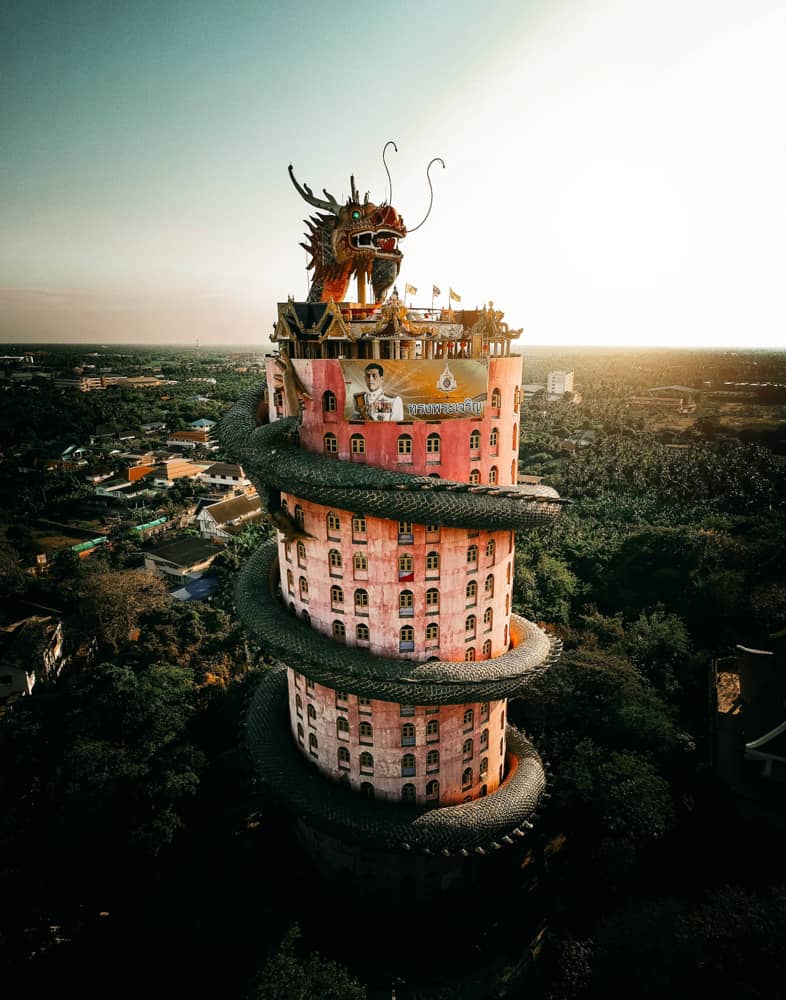 Der berühmte rosa Drachentempel in Bangkok: ein rosa zylindrischer Wolkenkratzer mit einer grünen Drachenstatue, die ihn umgibt.