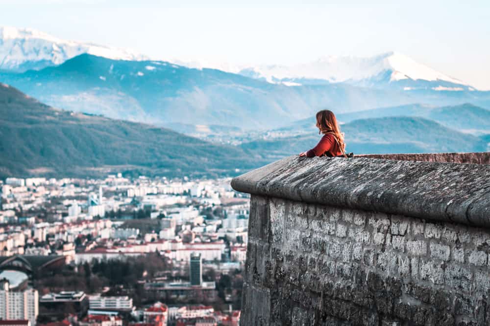 Chica mirando a Grenoble desde un muro sobre la ciudad