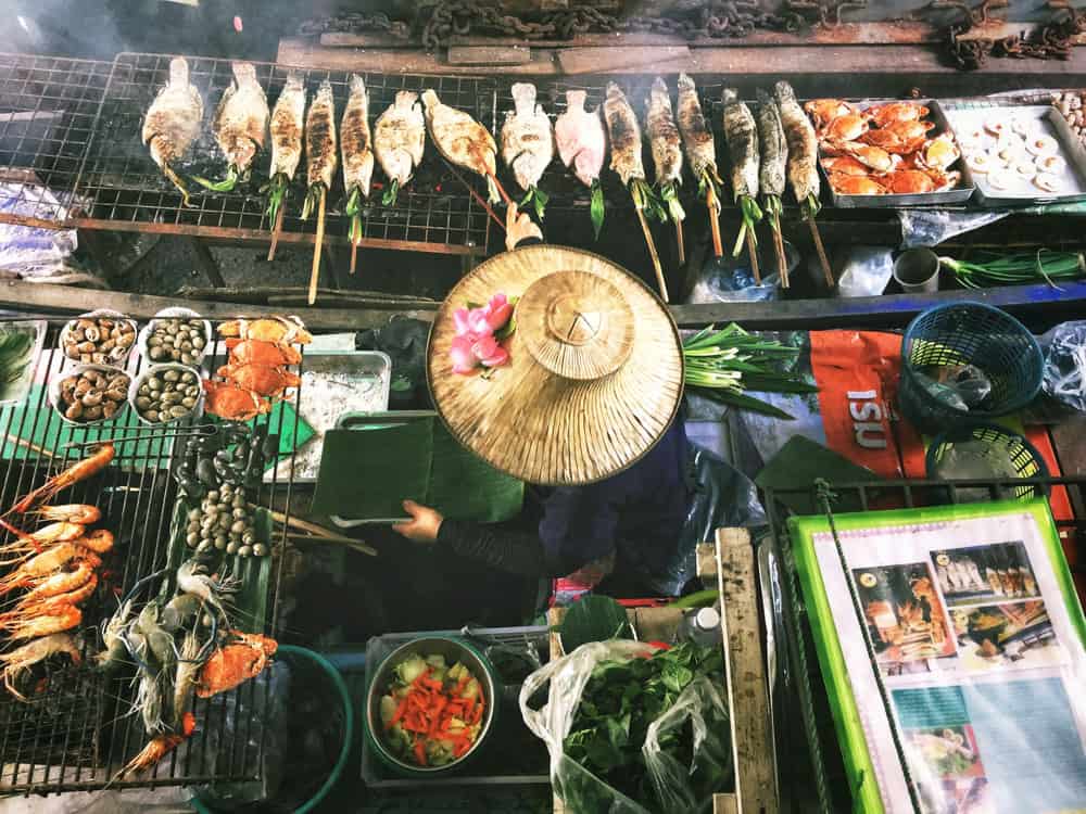 luchtfoto van een dame met een strohoed op, werkend bij een straat bbq in Bangkok city