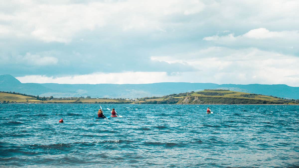 three people kayaking on slightly choppy blue waters in west cork, ireland
