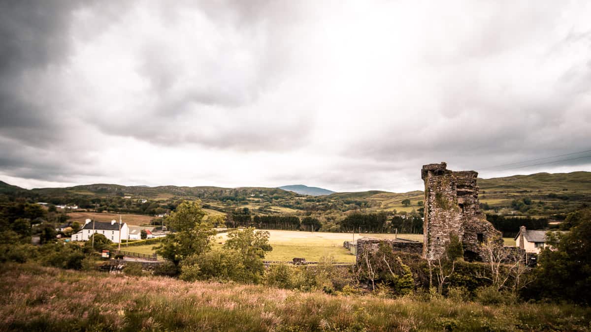 Carriganass Castle (eine Ruine) im Vordergrund, Felder und Ackerland bis zum Horizont an einem bewölkten, stimmungsvollen Tag im Westen von Cork