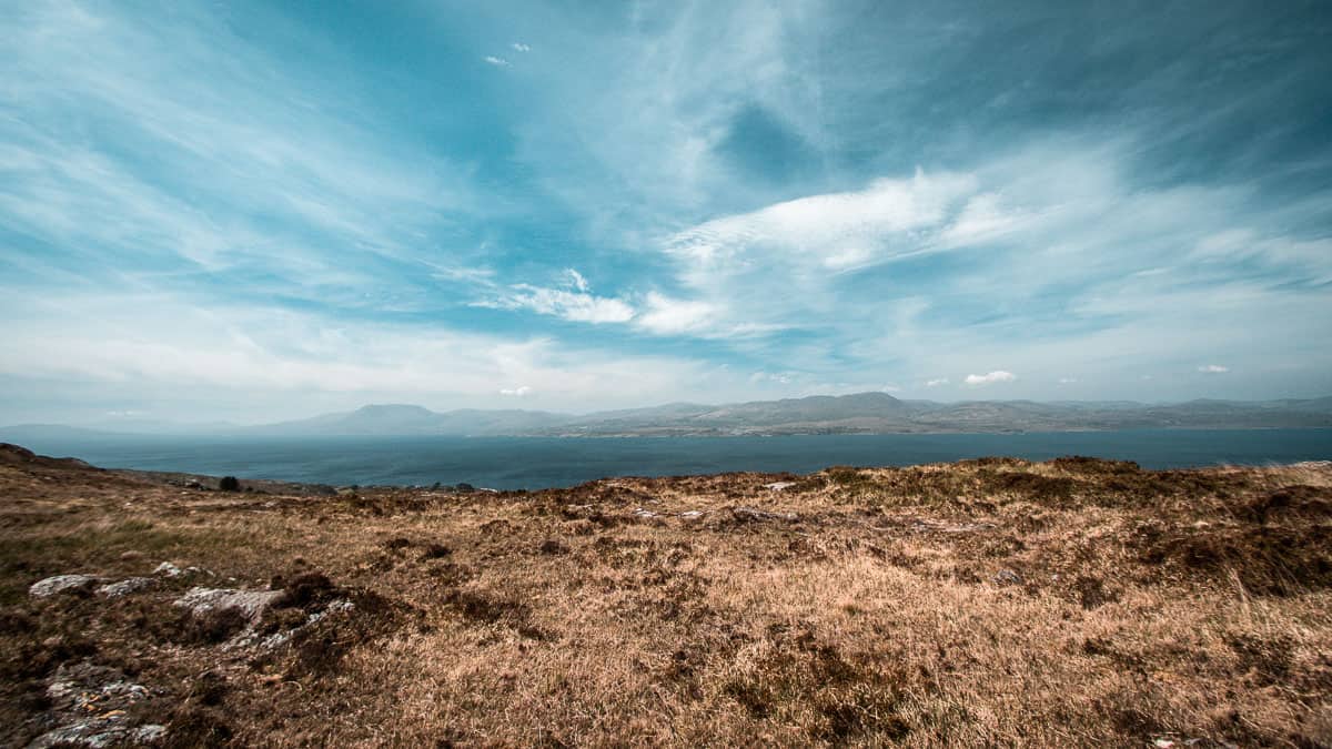 grote blauwe hemel boven ruige bergen met blauw water van bantry bay op de achtergrond