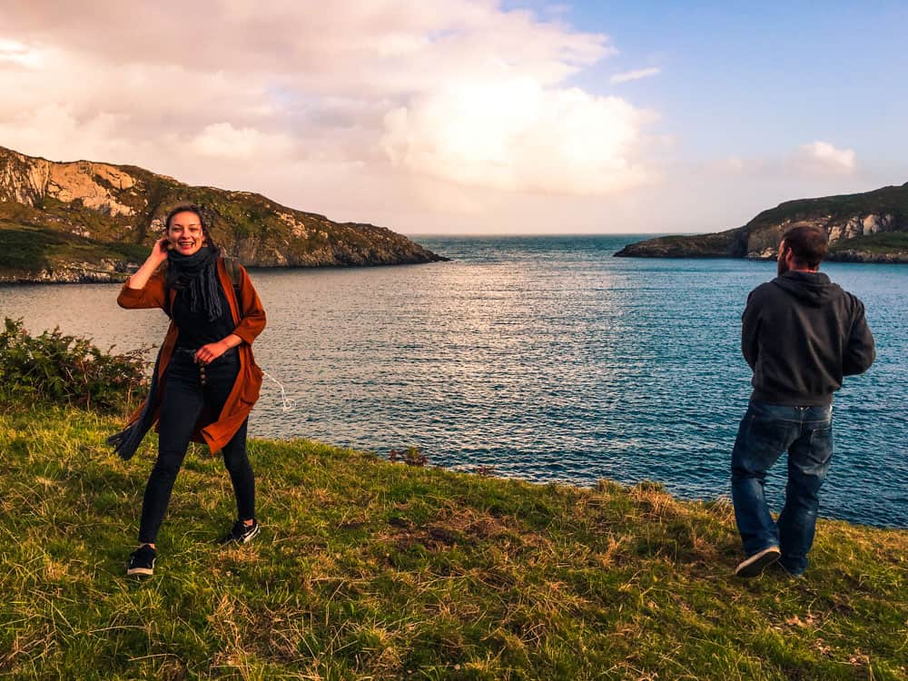 Two friends standing on the coastline overlooking Horseshoe Bay, Sherkin Island, County Cork at sunset.