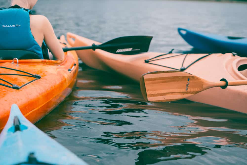 close up shot of 4 kayaks floating together on placid, dark waters.