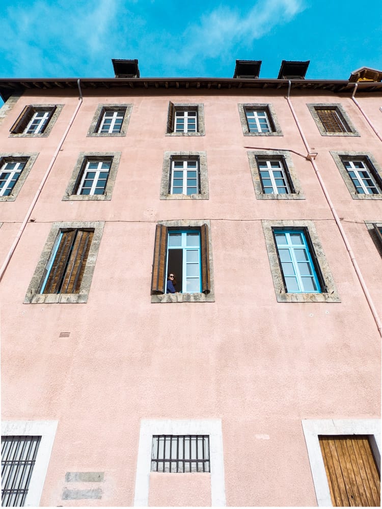 l'extérieur de l'espace de vie de la citadelle des nuages. le bâtiment est de couleur saumon. il y a une douzaine de grandes fenêtres. le ciel au-dessus est bleu vif.