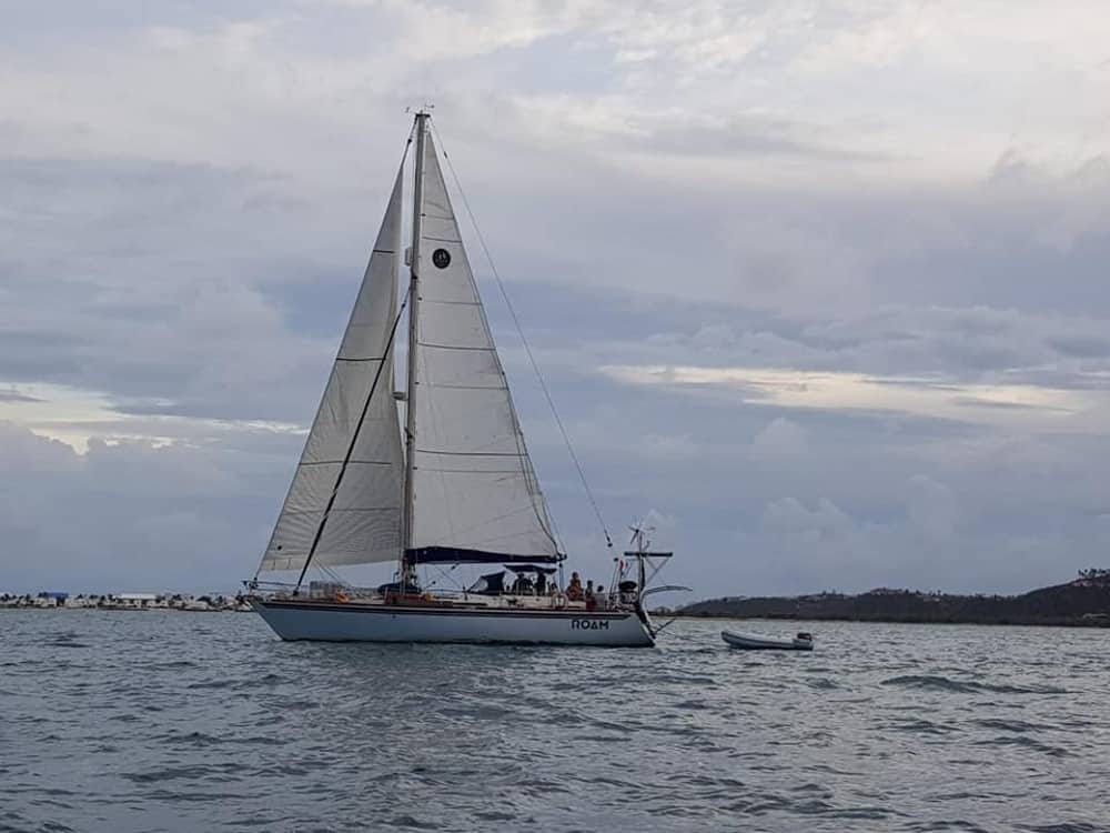 The Roam sailing vessel floating on the water with its sails up.