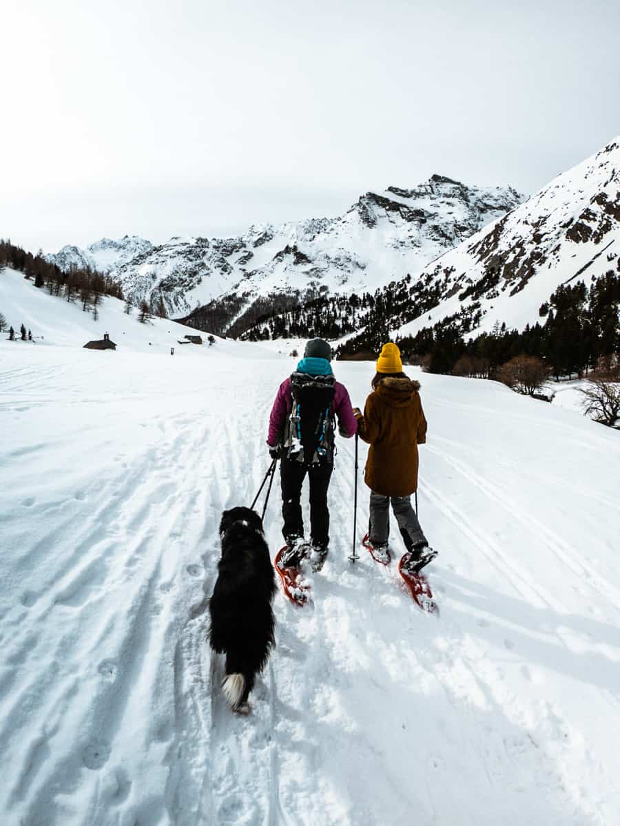 rachel, grace und kko, der hund, gehen mit schneeschuhen zurück zum auto, das gerade außerhalb von le monetier-les-bains geparkt ist