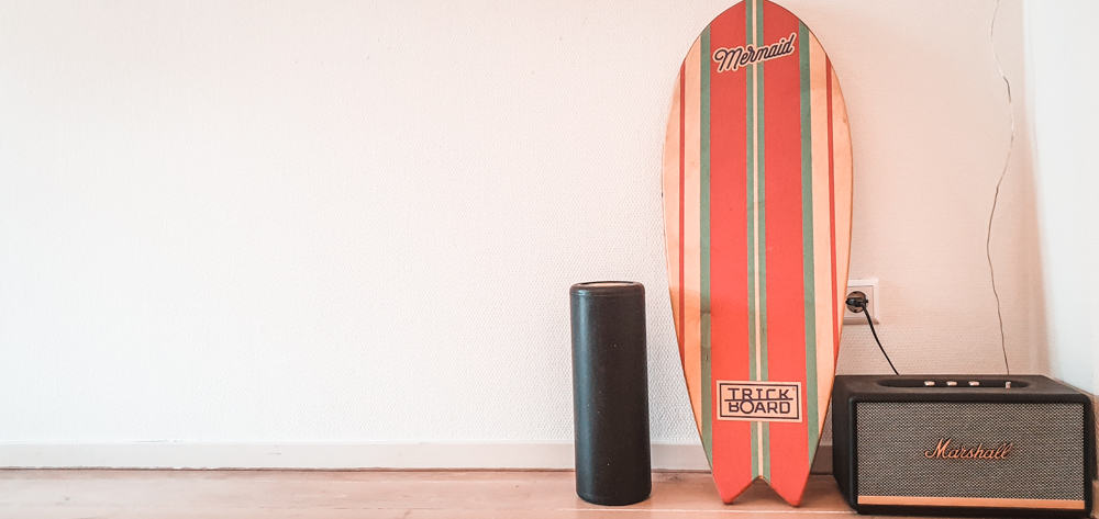 Matteo's indoboard (or balance board, wobble board, etc) leaning against a white wall next to a marshall speaker and a small black case.