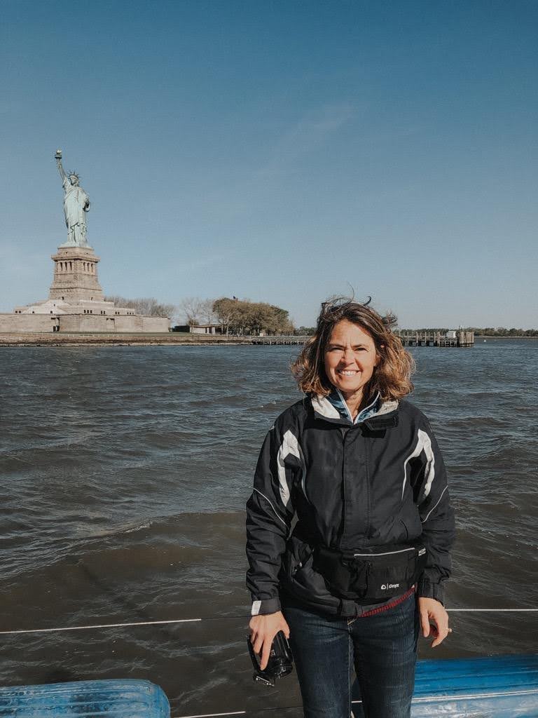 Rosa Linda sonriendo a bordo de su barco que está amarrado frente a la Estatua de la Libertad